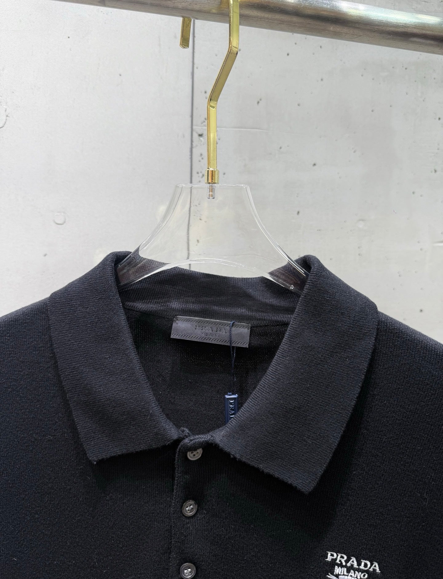 Black polo shirt collar close-up with button placket and PRADA chest logo