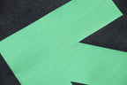 Green arrow X graphic on dark T-shirt front