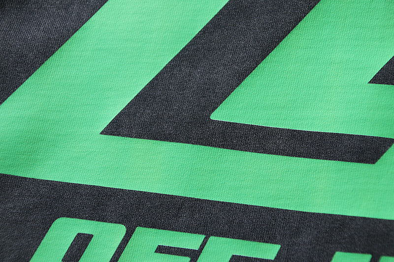 Black T-shirt close-up of green geometric logo and bold lettering