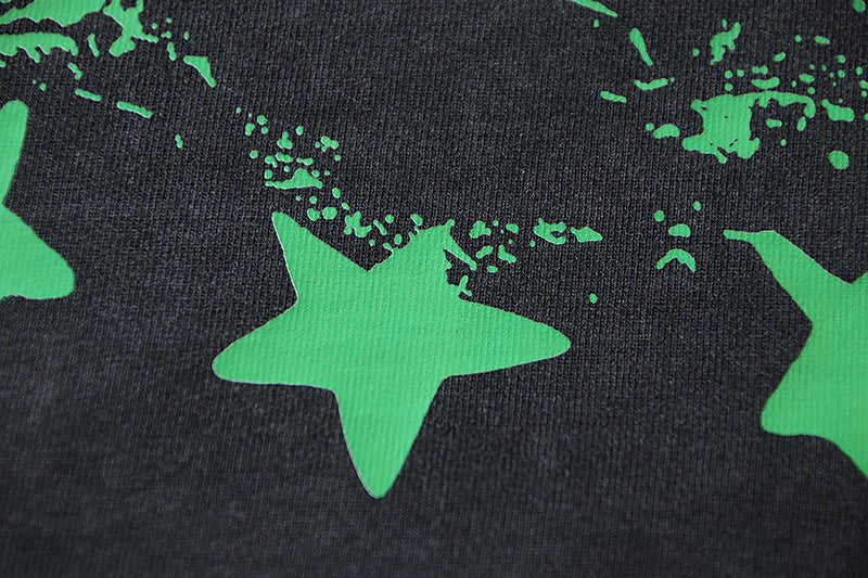 Black T-shirt graphic with large green star shapes and splatter accents