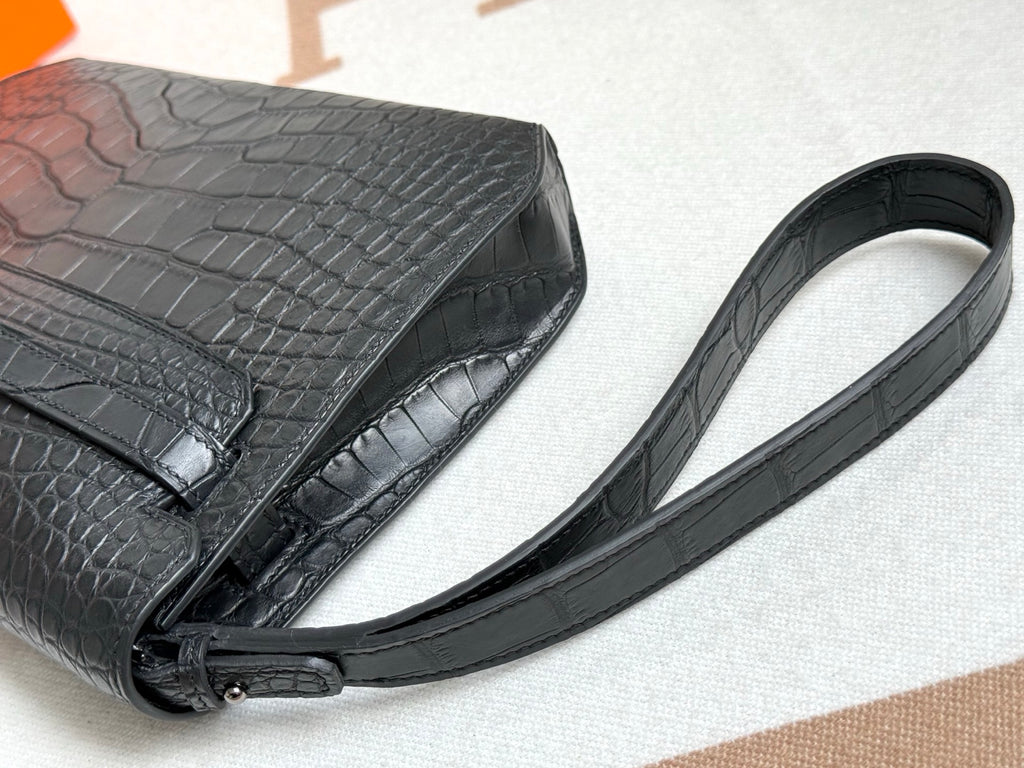 Hermes bag strap detail on dark crocodile-embossed leather with buckle and hardware