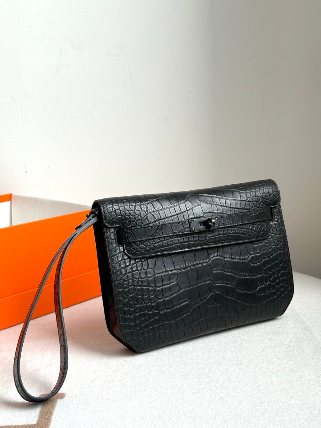Hermes bag with dark croc-embossed leather, front flap closure, and long wrist strap