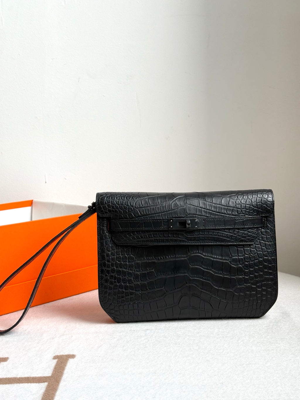 Hermes bag in dark crocodile-embossed leather with front flap and black wrist strap