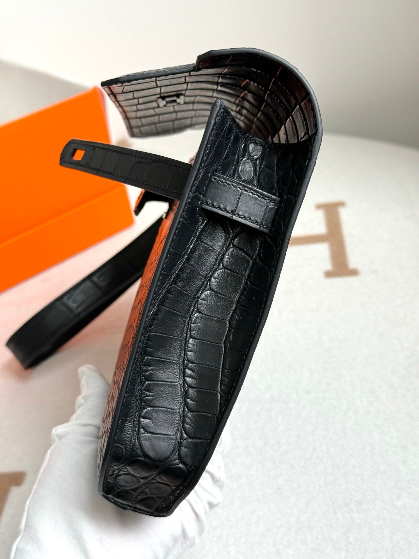 Hermes bag with dark crocodile-embossed finish, wrist strap, and interior compartment