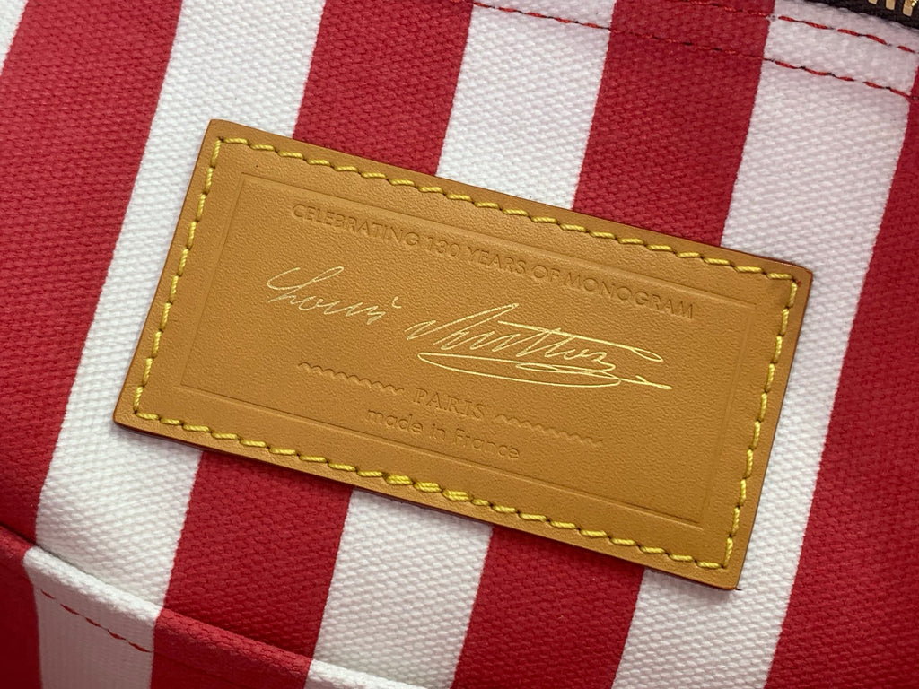 Leather brand patch on red-and-white striped tag on monogram bag
