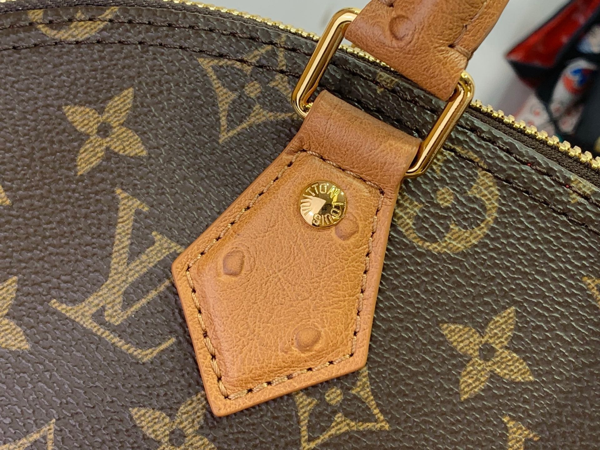 Louis Vuitton monogram bag strap with tan leather tab and gold-tone ring clasp.