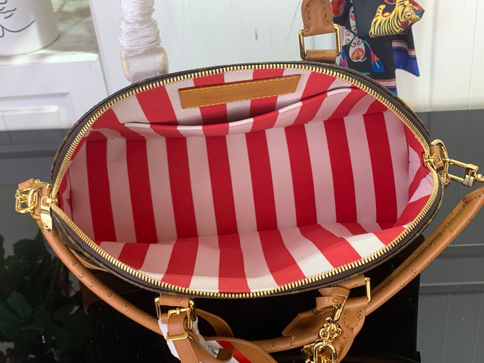 Louis Vuitton bag showing red-and-white striped fabric interior and zipper