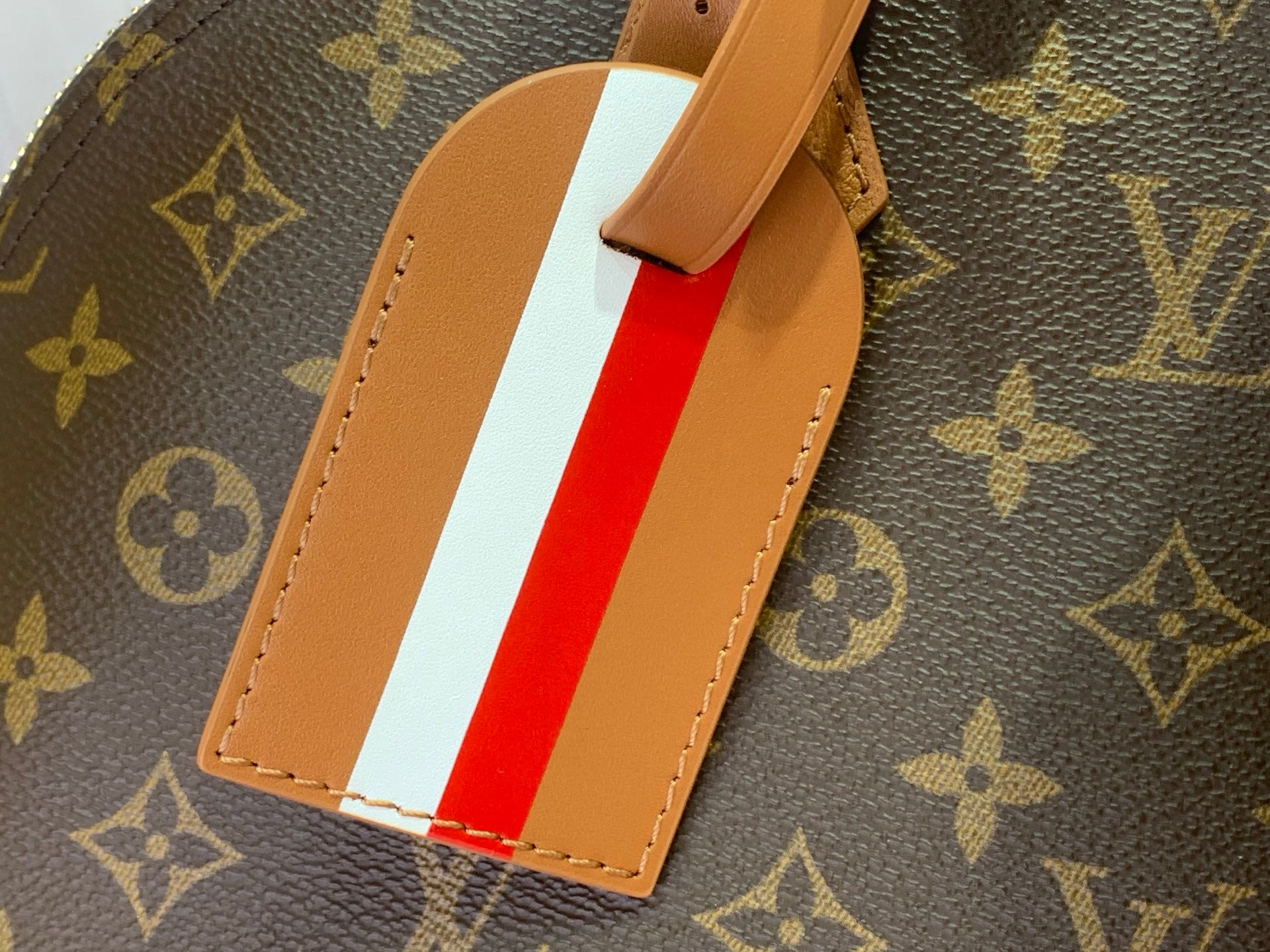 Striped leather luggage tag on monogram bag in red and white