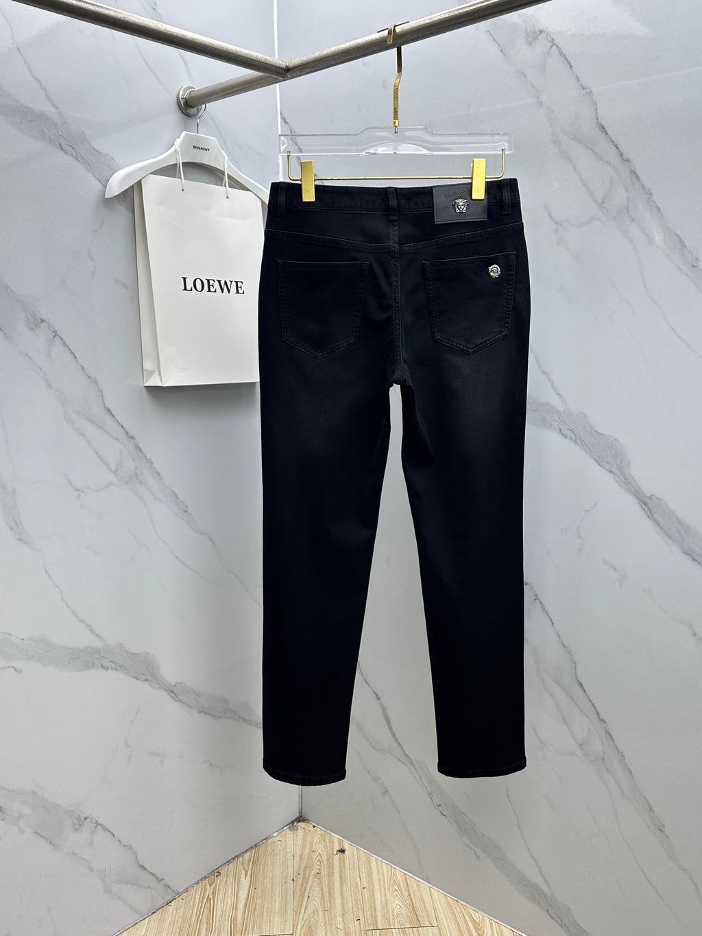 Versace dark blue denim jeans on a hanger, front view with button and pockets