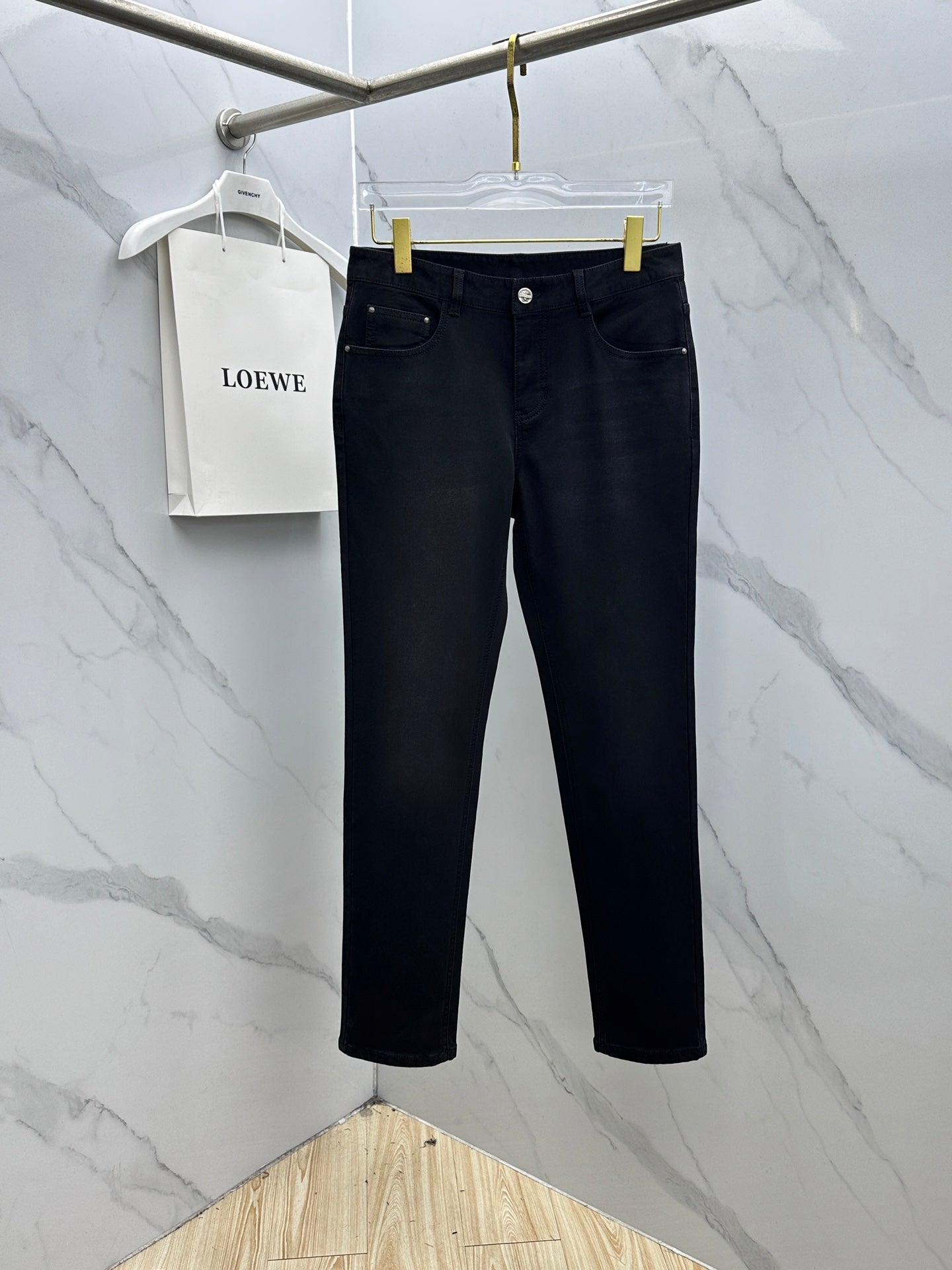 Versace dark blue jeans hanging on a hanger, straight-leg design with belt loops