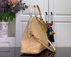 Beige tote bag angled side view with braided top handles and hanging charm