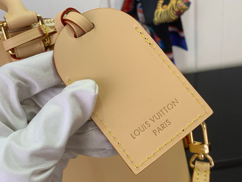 Beige leather tag with 'LOUIS VUITTON PARIS' lettering and yellow edge stitching