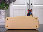 Beige tote bag back panel with gold corner hardware and rounded top edge