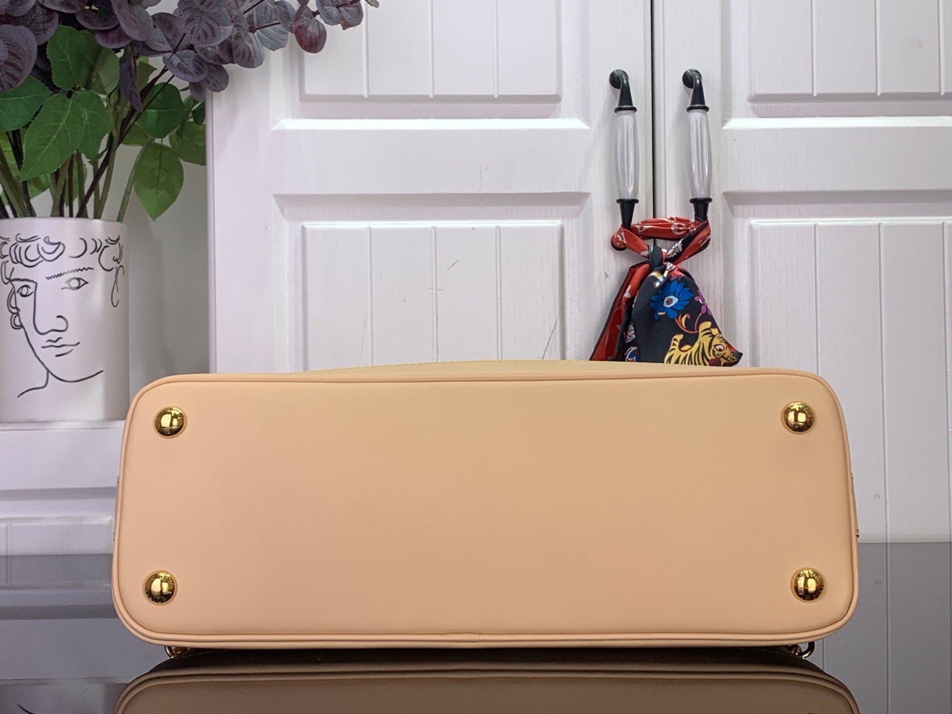 Beige tote bag back panel with gold corner hardware and rounded top edge