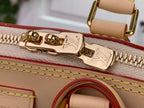 Gold zipper pull and hardware on beige tote bag with embossed logo detail