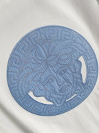 Versace T-shirt detail: large blue circular horse graphic embroidered on white.