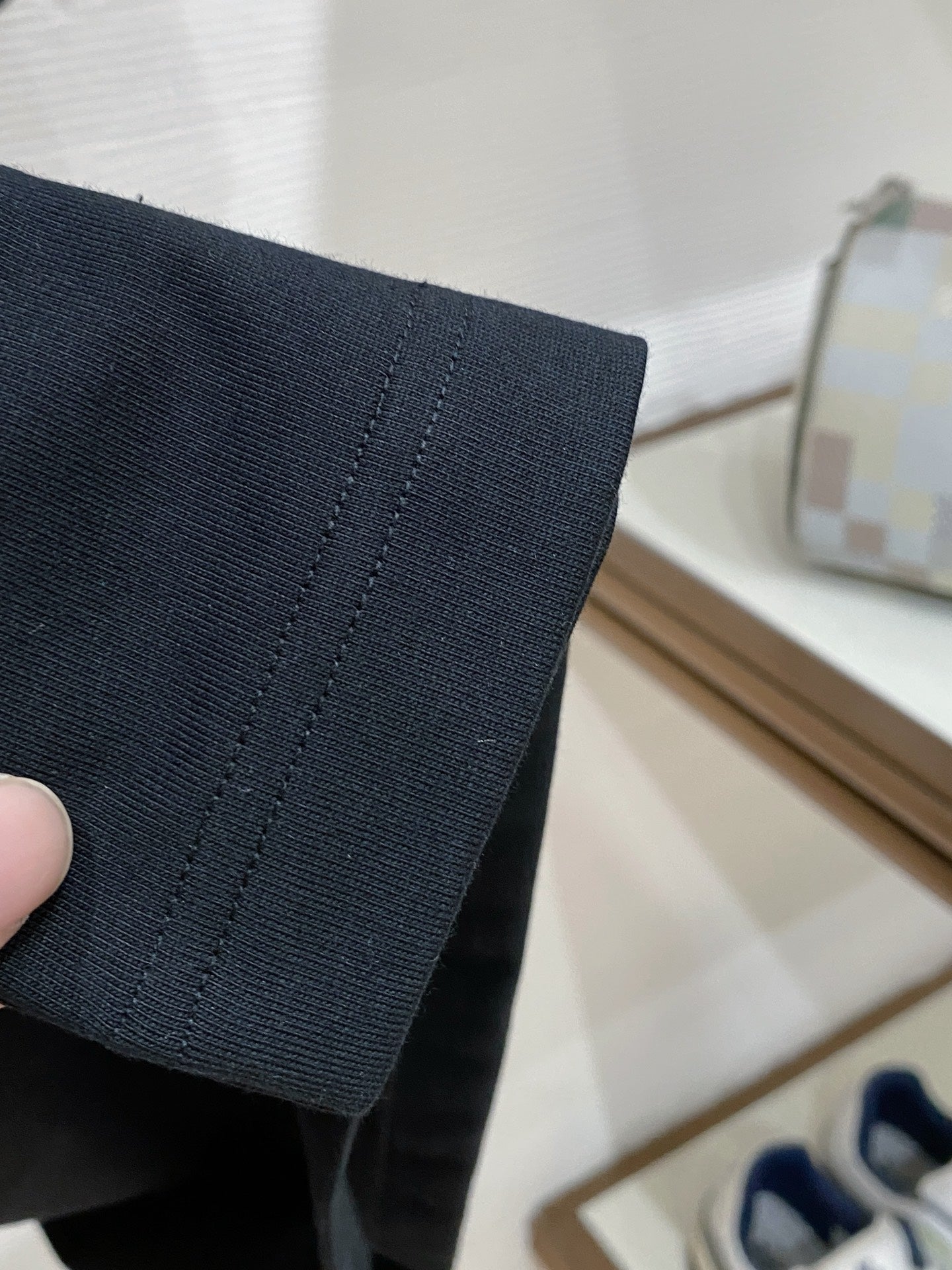 Dark navy T-shirt sleeve hem seam detail held in hand
