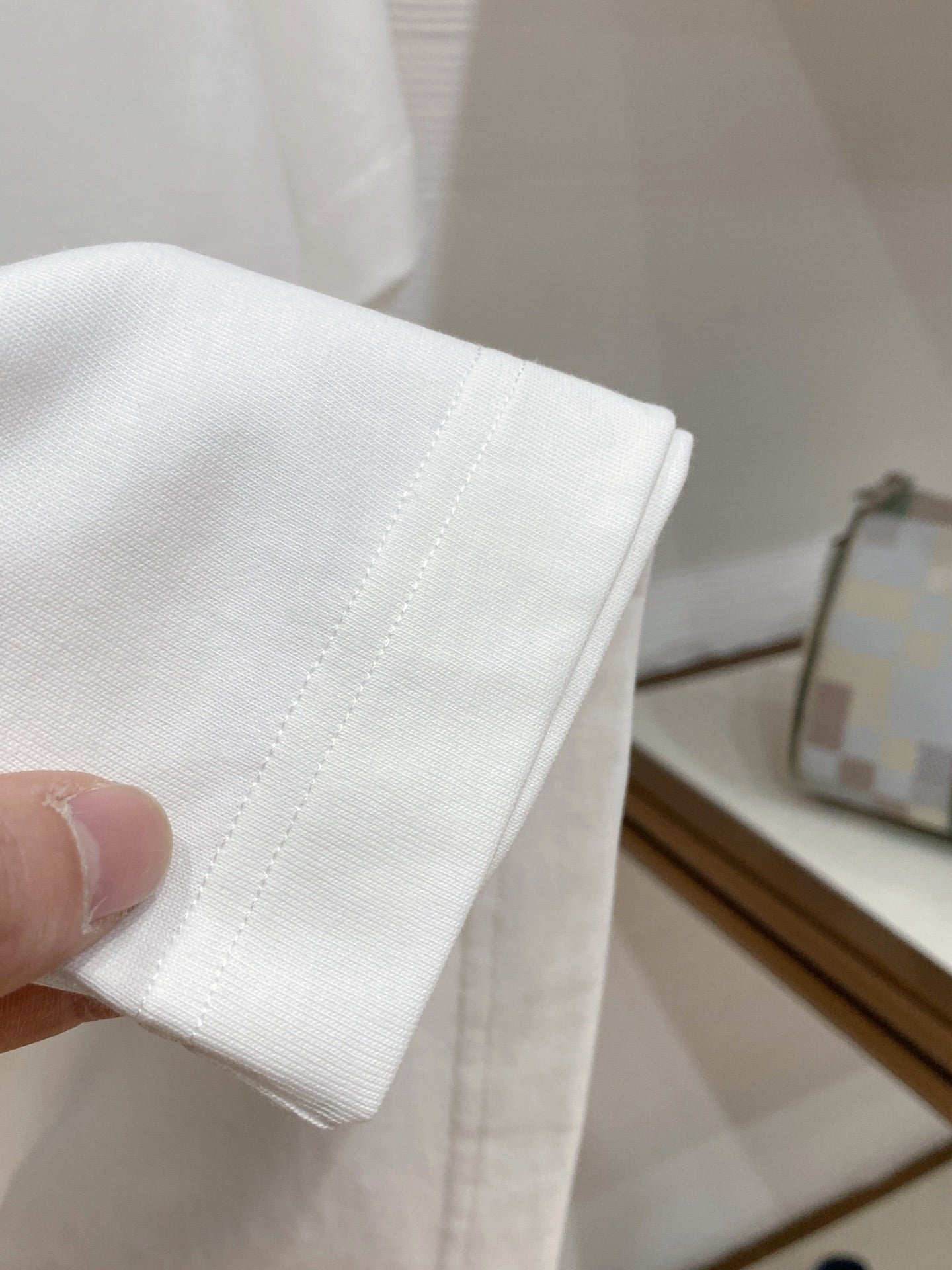 White T-shirt hem and stitching detail, close-up view.
