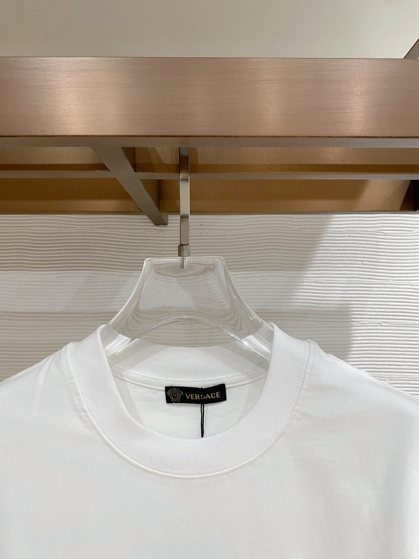 Versace T-shirt with crew neck and black neck label on white fabric.