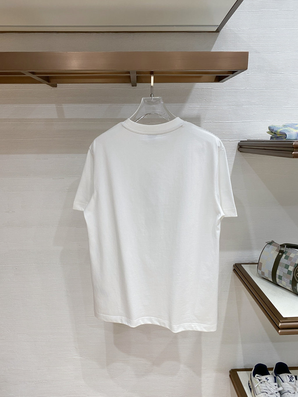 Versace T-shirt in white, hanging on a store rack.