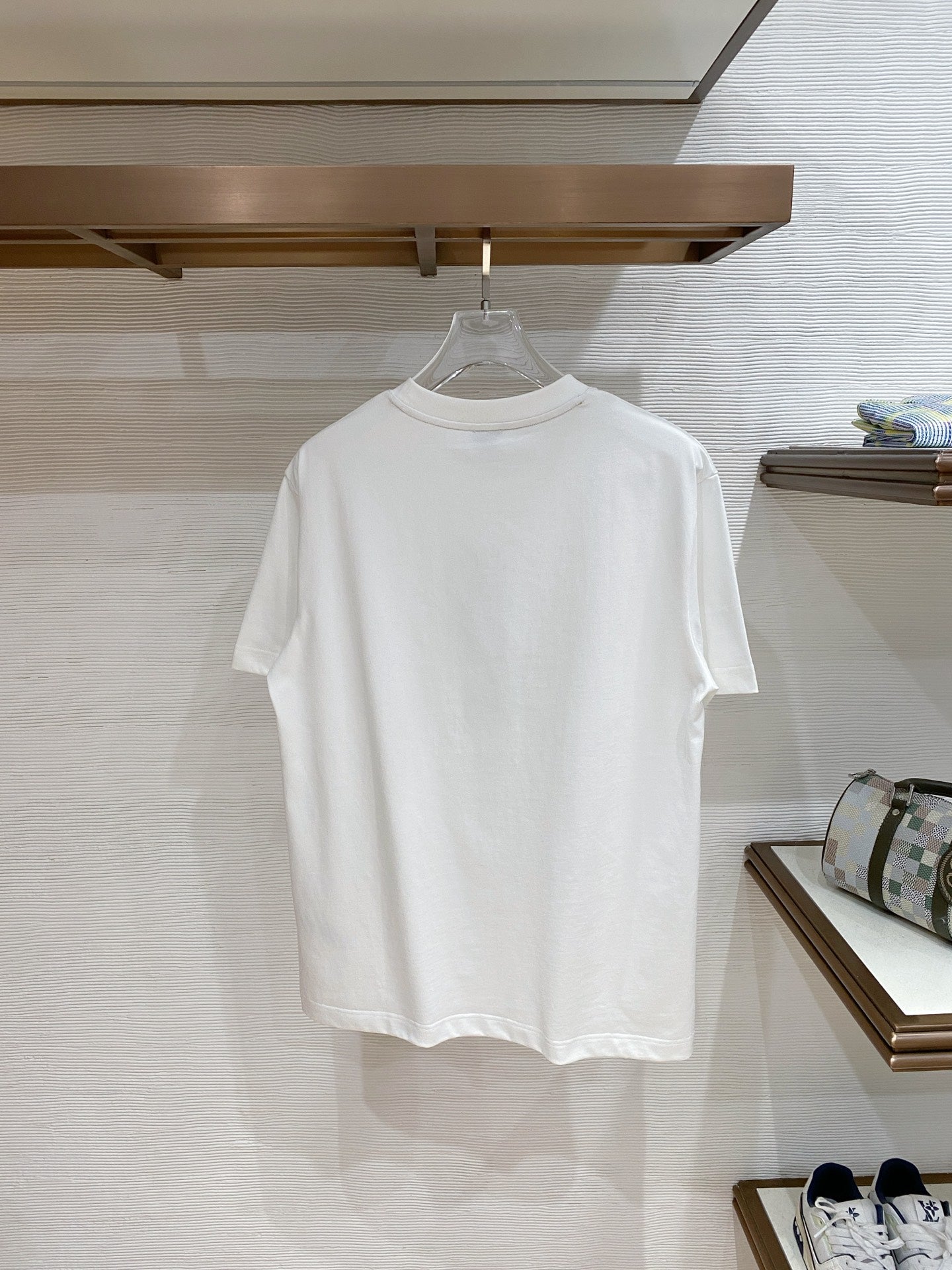 Versace T-shirt in white, hanging on a store rack.