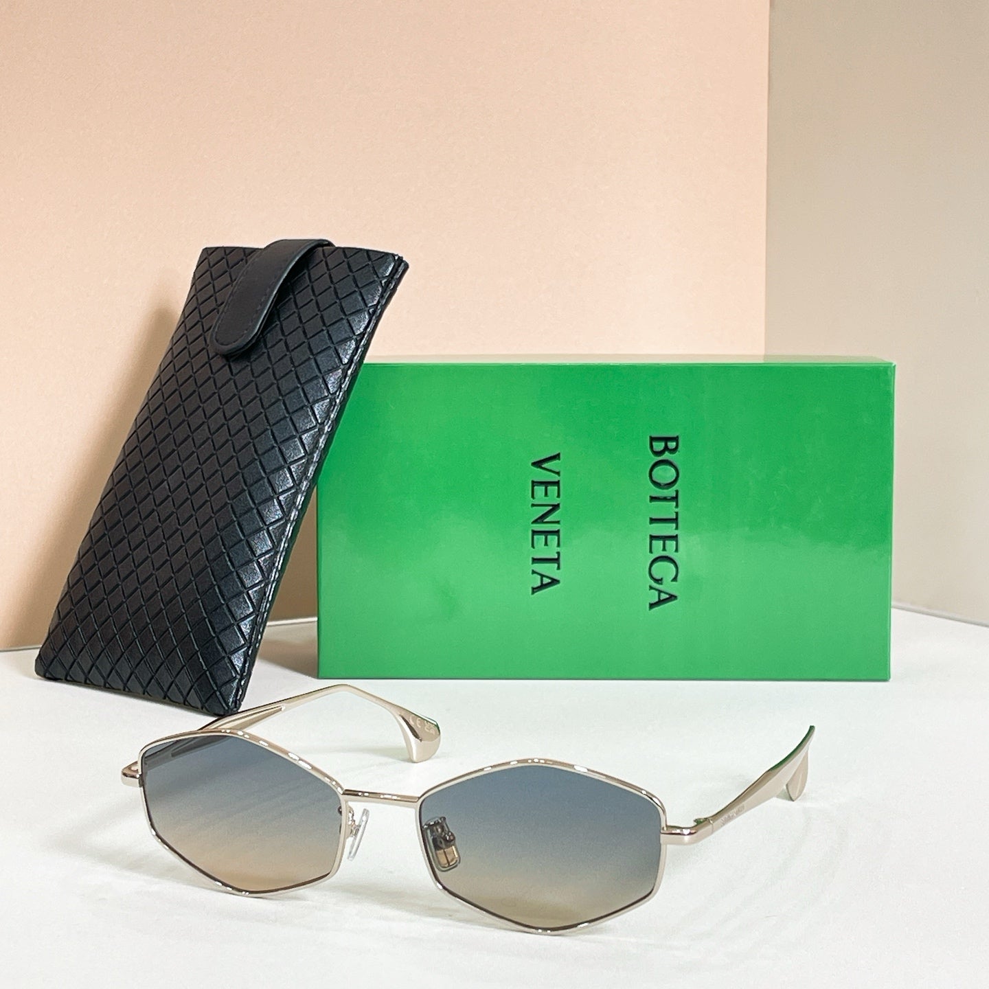 Sunglasses with beige lenses and gold-tone frames, shown with black textured case
