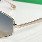 Close-up of gold-tone sunglasses frame with dark gradient lenses and nose bridge