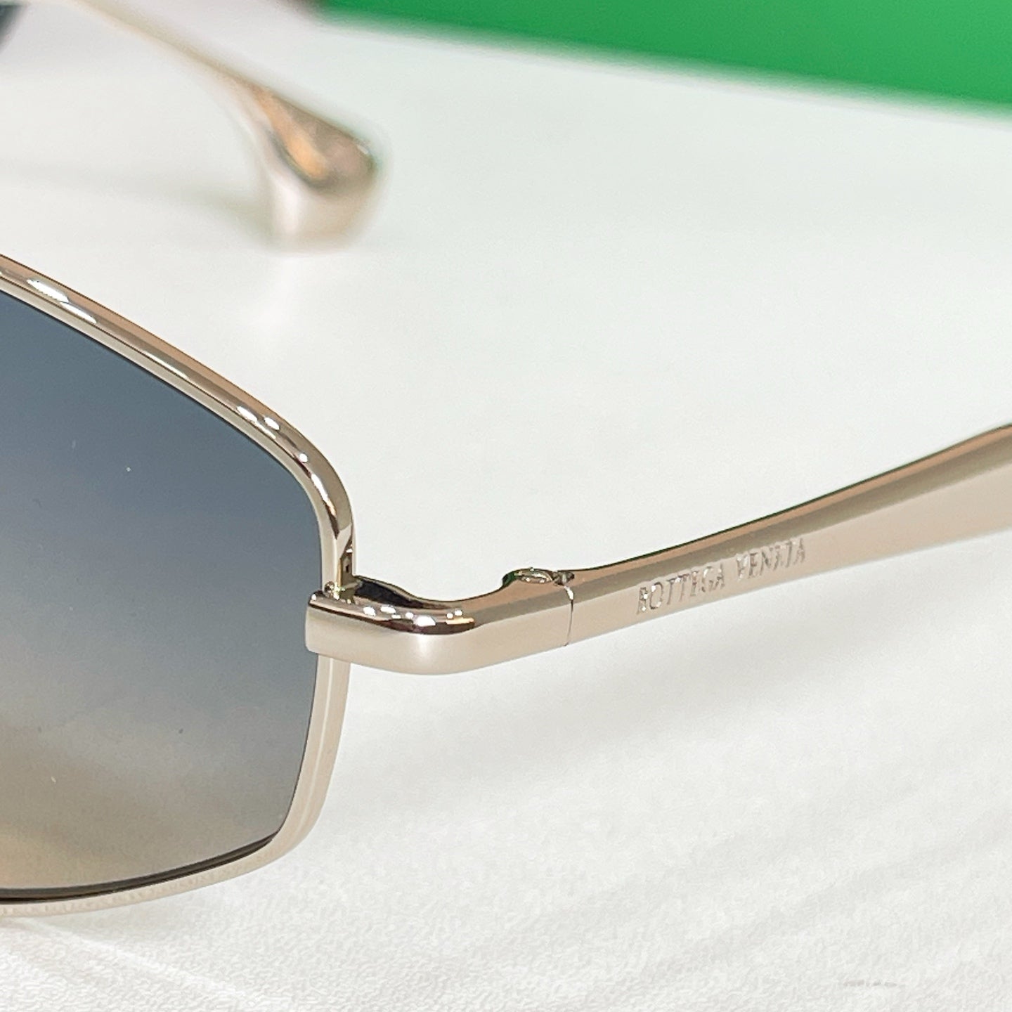 Close-up of gold-tone sunglasses frame with dark gradient lenses and nose bridge