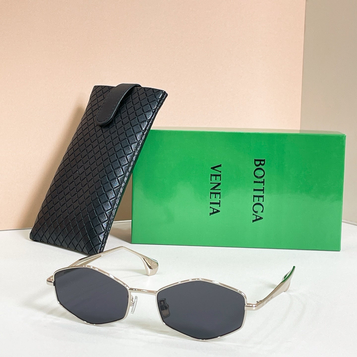 Sunglasses with dark lenses and gold-tone frames, shown with black textured case