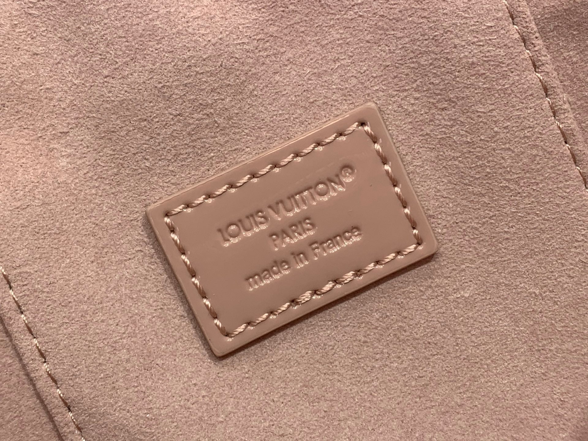 Louis Vuitton leather label on mauve handbag reading Louis Vuitton Paris, made in France
