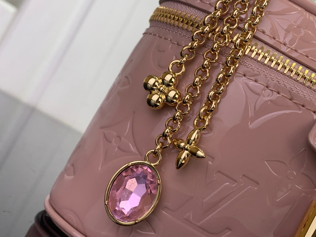 Louis Vuitton handbag charm detail with pink gem on mauve embossed leather and gold chain