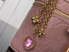 Louis Vuitton handbag charm detail with pink gem on mauve embossed leather and gold chain