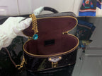 Black patent monogram handbag with burgundy interior pocket and gold zipper trim
