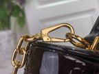 Gold clasp and chain on glossy black handbag strap