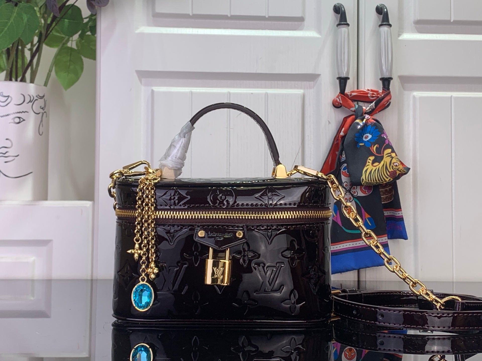 Louis Vuitton patent monogram handbag with blue gem charm and gold chain strap
