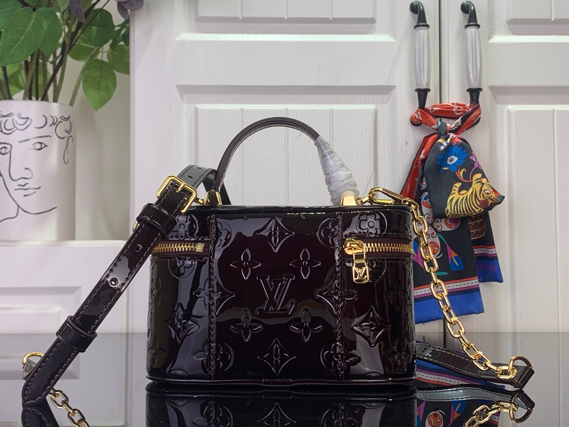 Black glossy monogram handbag with structured top handles and gold chain strap