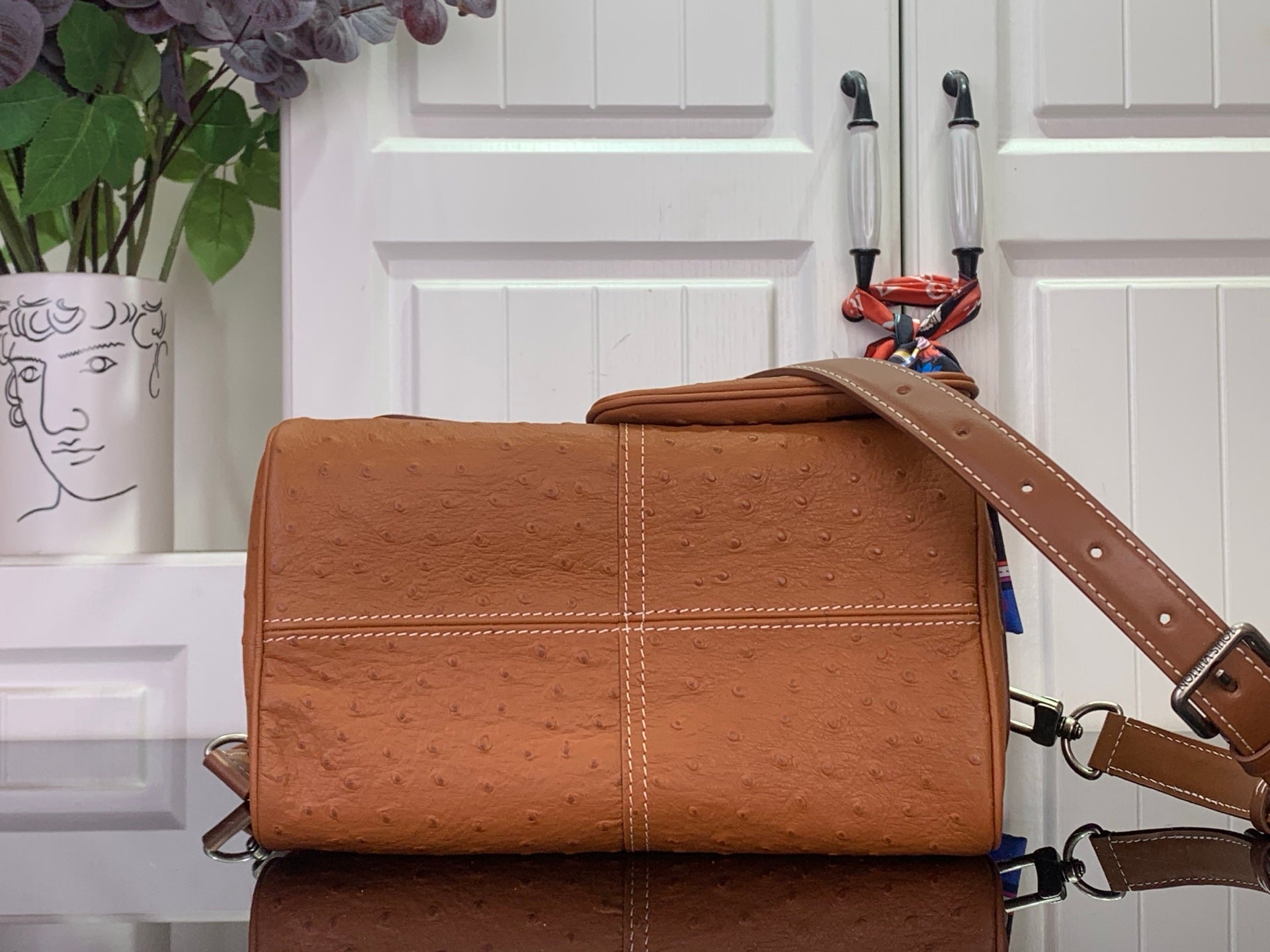 Tan leather Louis Vuitton fold-over bag with stitched panels and crossbody strap.