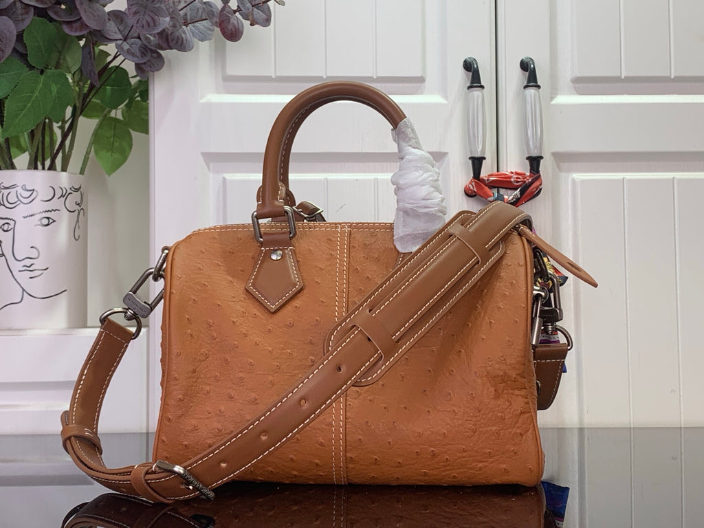 Tan leather Louis Vuitton tote with top handle, long shoulder strap and stitched front panels.