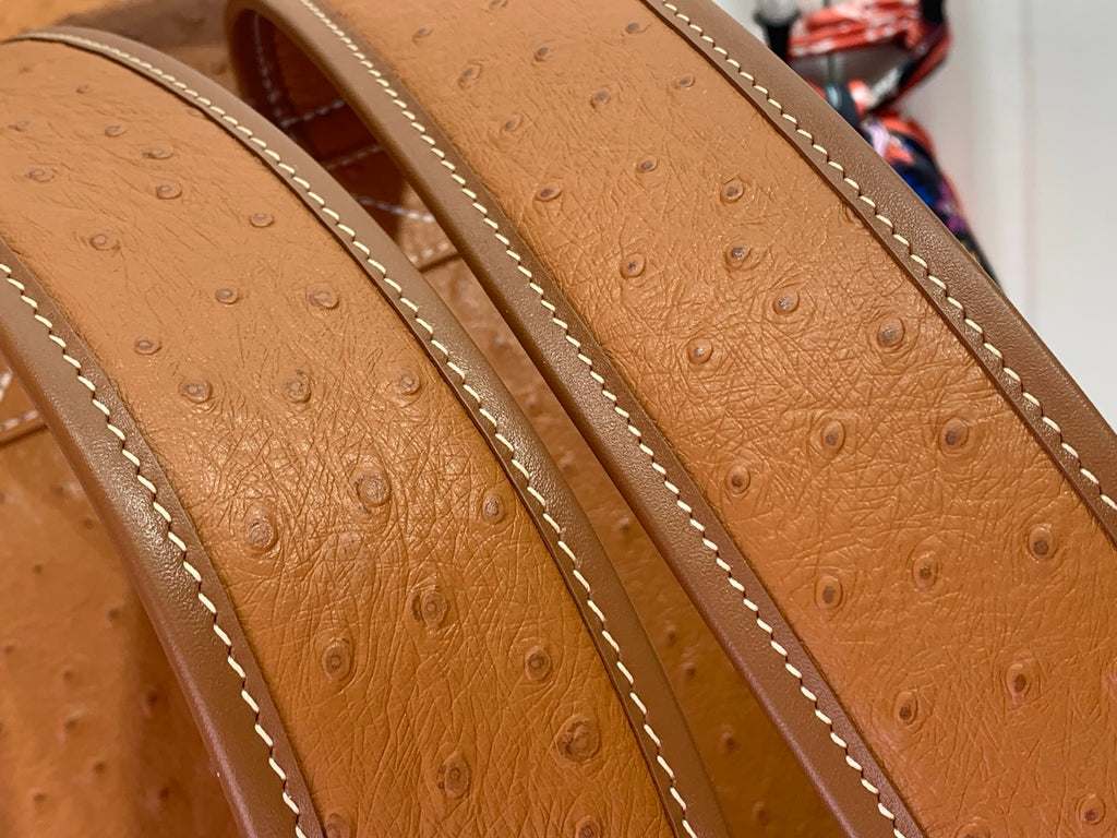 Tan pebbled leather backpack straps with contrast stitching and raised texture