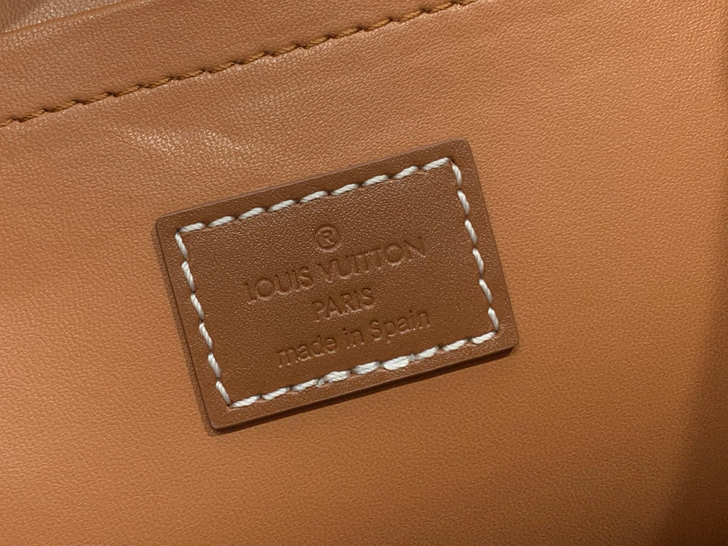 Louis Vuitton leather logo patch with stitched border on tan leather.