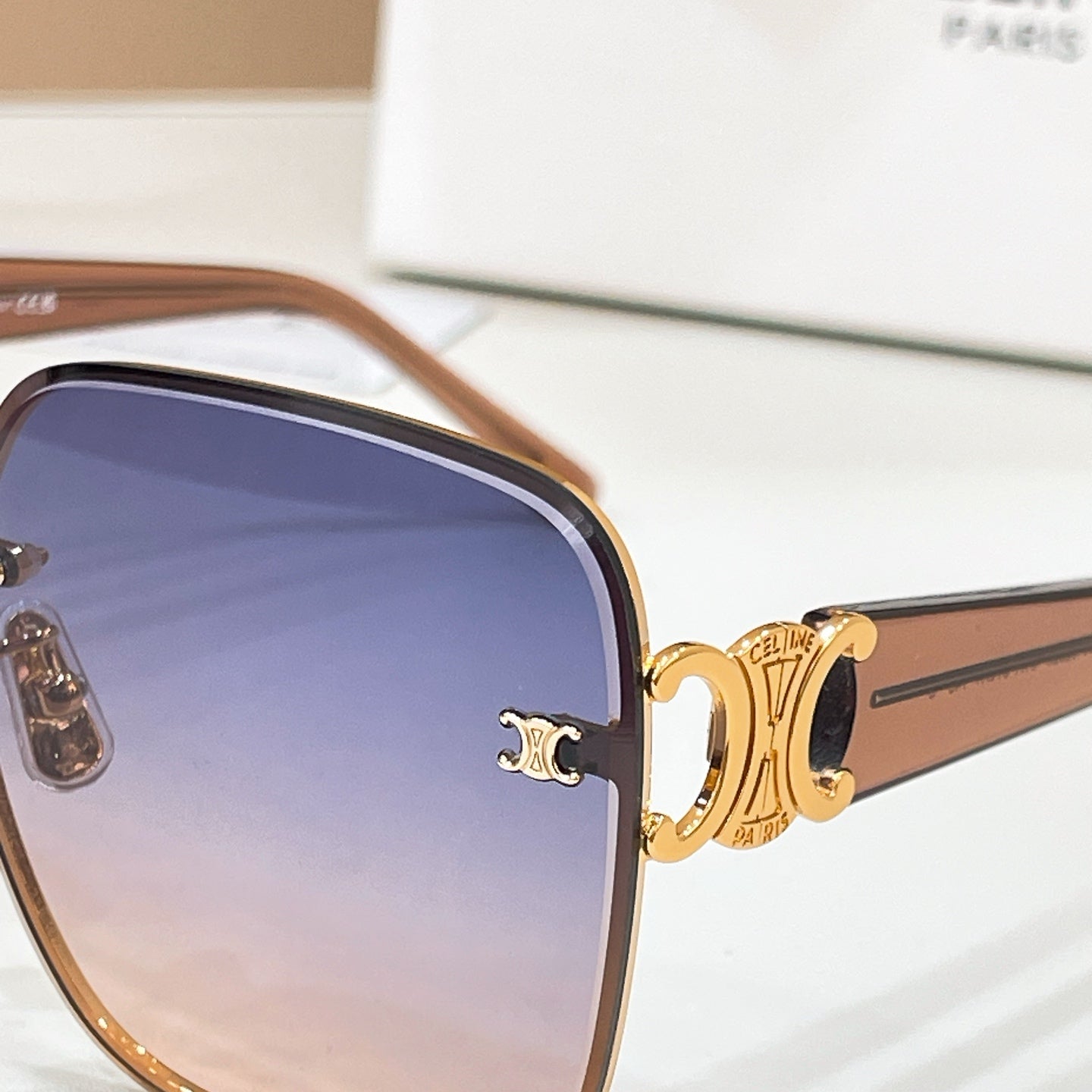 Celine sunglasses close-up: gold logo on frame with blue gradient lenses