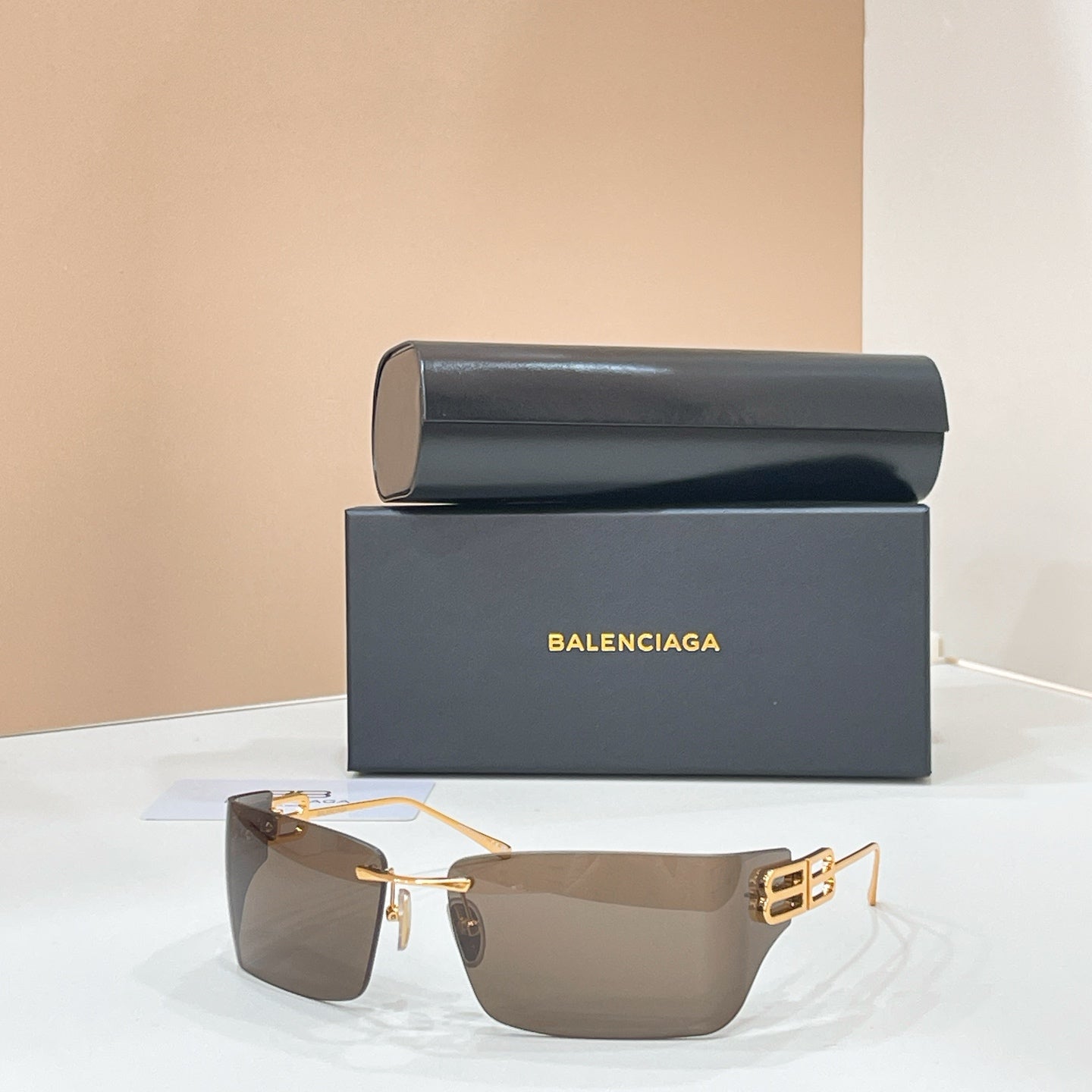Sunglasses with gold-tone frame and brown-tinted lenses, geometric temple logo detail.
