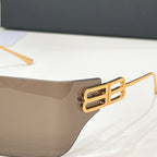 Sunglasses temple close-up with gold-tone geometric logo and translucent lens edge.