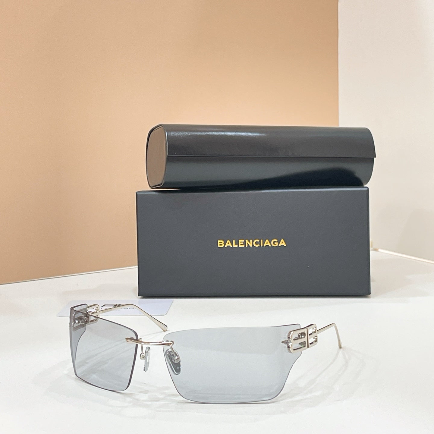 Sunglasses with gold-tone frame and clear lenses, geometric logo detail at temples.