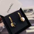 Chanel stud earrings with black and white round charms and gold-tone logo details
