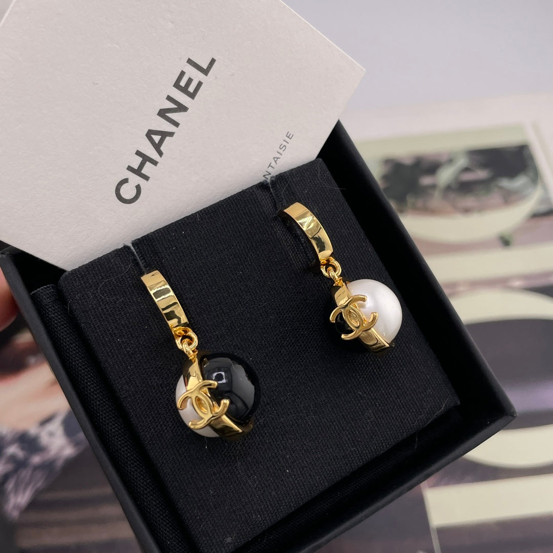Chanel stud earrings with black and white round charms and gold-tone logo details
