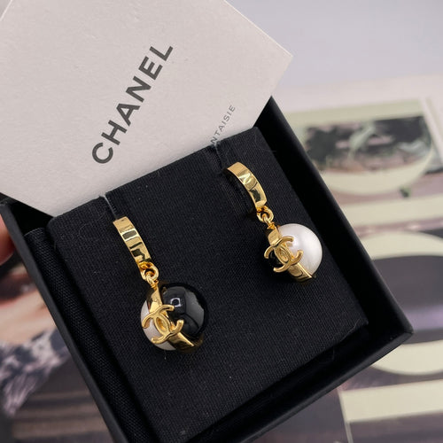 Chanel stud earrings with black and white round charms and gold-tone logo details