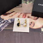 Chanel earrings shown with black and white round charms and gold-tone hoops