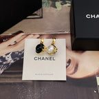 Chanel earrings with gold-tone hoops and black and white round charms on card