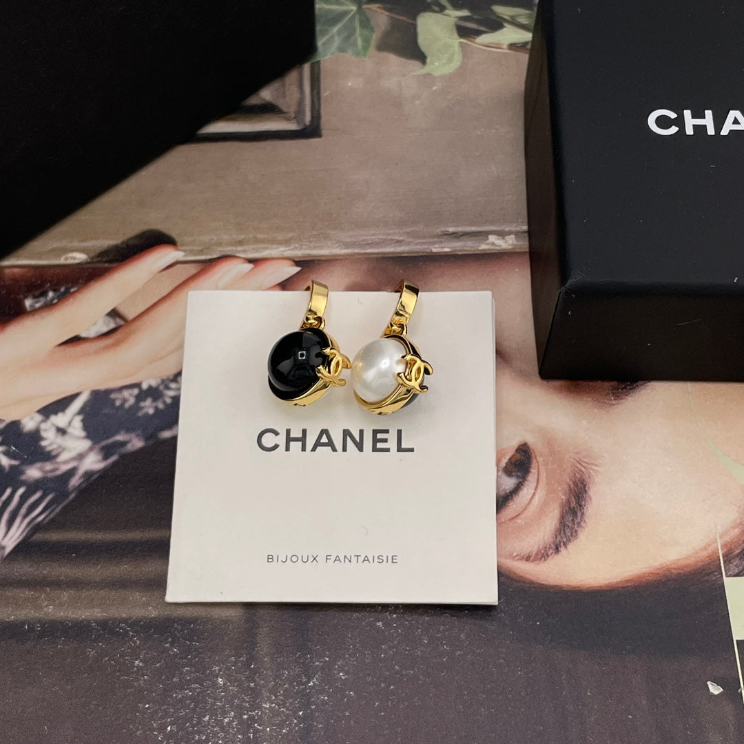 Chanel earrings with gold-tone hoops and black and white round charms on card